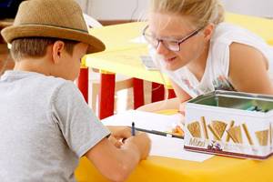 Ein Kind mit Stift am Tisch im Hotel Colonna Country & Sporting Club