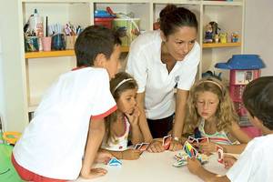Erzieherin und Kinder spielen eine Karte im Kindergarten