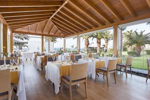Innenbereich des Hipotels Natura Palace Restaurants mit Blick auf das Meer und Palmen.