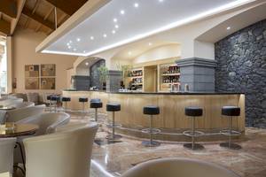 Barbereich des Hipotels Natura Palace mit Holzbar, Barhockern und Dekor.