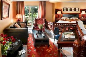 Innenansicht der Suite im Palmeraie Palace mit Bett, Wohnzimmer und Schreibtisch.