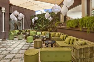 Lounge-Bereich im Palmeraie Palace Hotel mit grünen Sofas, Tischen und dekorativen Lampen.