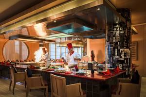 Restaurant im Beach Rotana Hotel mit Köchen, die vor einer offenen Flamme kochen.