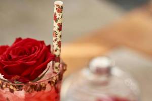 Ein roter Cocktail in einem Glas mit einer roten Rose auf einem Strohhalm
