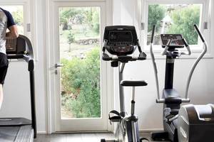 Mann läuft auf einem Laufband im Fitnessraum des Hotels Myconian Korali Relais & Chateaux.