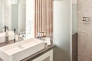 Hotelbadezimmer von Myconian Korali Relais & Chateaux mit modernem Design und Marmorwänden.