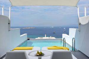 Terrasse mit Meerblick im Myconian Korali Relais & Chateaux mit gelben Handtüchern und einer Schale mit Früchten.