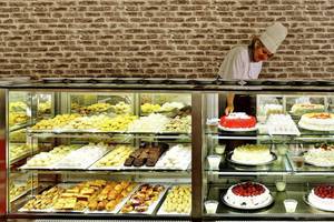 Eine Konditorin im Side Royal Paradise Hotel bereitet Kuchen zu, die in einer Vitrine ausgestellt sind.
