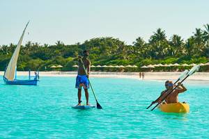 Zwei Männer paddeln auf dem Barefoot Eco Hotel, einer Segelboot ist im Hintergrund
