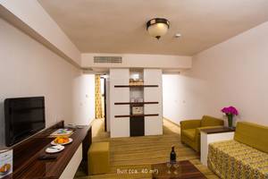 Innenansicht der Suite im Defne Star Hotel mit Fernseher, Obstteller, Weinflasche, Sofas und Schreibtisch.