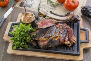 Gegrillter Steakteller mit Salat und Tomaten auf einem Holztisch