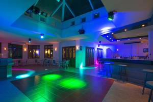 Innenansicht der Disco im Iberostar Creta Panorama & Mare Hotel mit bunten Lichtern und Sitzgelegenheiten.