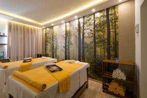 Spa-Behandlungsraum im Iberostar Creta Panorama & Mare Hotel mit zwei Massagetischen und einem großen Wandbild von Bäumen.