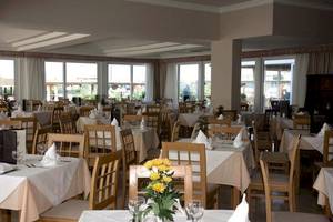 Innenansicht des Restaurants im Astir Beach Hotel mit gedeckten Tischen und gelben Blumen.