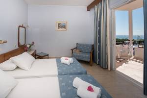 Zimmer mit Meerblick im Astir Beach Hotel auf Zakynthos mit zwei Betten, Balkon, Tisch und Stühlen.