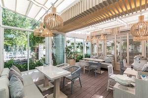 Innenbereich des Cape Panwa Hotels mit Tischen, Stühlen und Pflanzen.