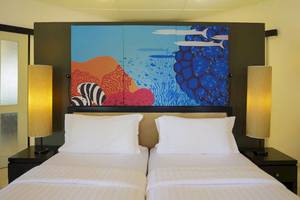 Doppelbett-Zimmer im Angsana Velavaru mit farbenfrohem Wandbild und zwei Nachttischen mit Lampen.