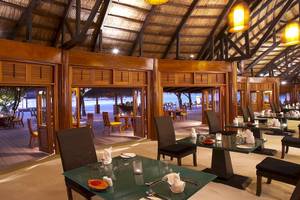 Innenansicht des Restaurants im Angsana Velavaru Hotel mit Holzdekoration und Meeresblick.