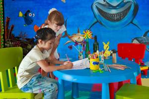 Kinderzimmer im Angsana Velavaru Hotel mit einer Wandmalerei von Haien und Fischen.