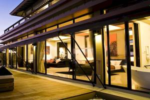 Außenbereich des Angsana Velavaru Hotels mit Terrasse, Loungebereich und großen Glasfenstern.
