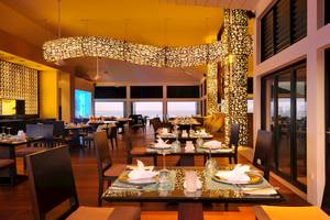 Innenansicht des Restaurants im Angsana Velavaru Hotel mit dekorativ beleuchteten Strukturen und offenen Türen zum Meer.