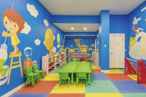 Kinderzimmer im Glamour Resort & Spa mit blauen Wänden, buntem Boden und Spielmöbeln.