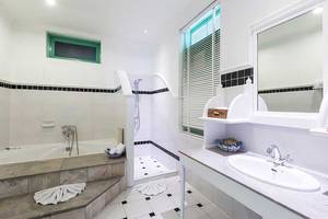 Badezimmer im Cape Panwa Hotel mit Badewanne, Dusche, Waschbecken und Spiegel.