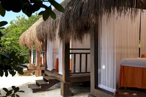 Hütten im Paradisus Playa del Carmen Hotel auf Sandstrand mit weißen Vorhängen und orangefarbenen Tischdecken.