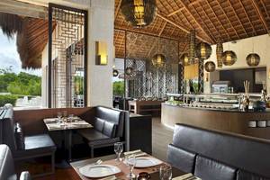 Innenraum des Paradisus Playa del Carmen Hotels mit modernem Design, schwarzen Ledersofas und einer Theke mit Essensangeboten.