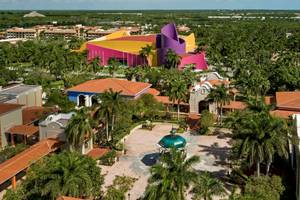 Luftaufnahme des Iberostar Paraiso del Mar Hotels, umgeben von Gebäuden, Palmen und Bäumen.
