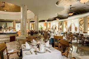 Innenansicht des Restaurants im Iberostar Paraiso del Mar Hotel mit geräumigen Tischen und Stühlen, einem eleganten Buffet und einer geräumigen Atmosphäre.