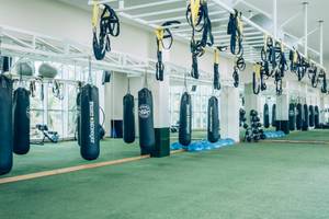 Fitnessstudio mit Boxsäcken und Trainingsgeräten an der Decke hängend.