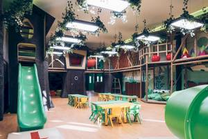 Der Kinderspielbereich des Iberostar Paraiso del Mar mit bunten Farben, Tischen, Stühlen und Spielgeräten.