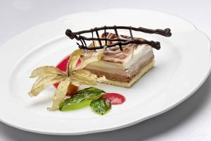Dessert auf einem weißen Teller mit Schokoladen- und Fruchtdekoration.