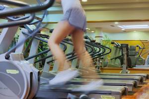 Fitnesscenter im H10 Playa Meloneras Palace mit mehreren Laufbändern, eine Person in Bewegung.
