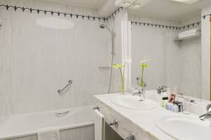 Badezimmer im H10 Playa Meloneras Palace mit Badewanne, Dusche, Waschbecken und Spiegeln.