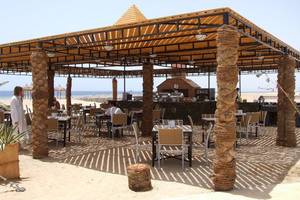 Außenterrasse des Gorgonia Beach Resorts mit Tischen und Stühlen unter einem Dach