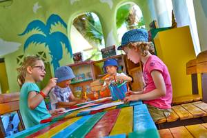 Vier Kinder sitzen am Tisch und schreiben im Kinderzimmer des Odyssee Resorts.