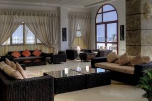 Hotellobby des Gorgonia Beach Resorts mit Sofas, Tischen und großen Fenstern.