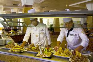 Zwei Mitarbeiter eines Gorgonia Beach Resorts servieren Essen in einem Restaurant.