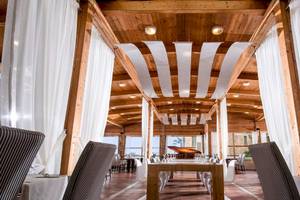 Innenbereich des Bella Beach Hotels mit Esstisch, Stühlen und weißen Vorhängen.