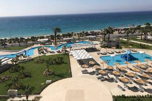 Luftaufnahme des Akti Imperial Deluxe Resorts & Spa mit mehreren Swimmingpools und Sonnenliegen am Strand.