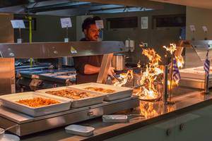 Ein Mann grillt Essen in einem Restaurant des Akti Imperial Deluxe Resort & Spa.
