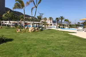 Poolbereich des Akti Imperial Deluxe Resorts mit Palmen und Liegestühlen.