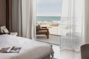 Bett im Hotelzimmer des Jumeirah at Saadiyat Island Resort mit Ausblick auf den Strand.