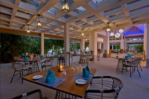 Innenansicht des Restaurants des Kandima Maldives Hotels mit gedeckten Tischen und hängenden Lampen.