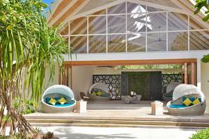 Außenbereich des Kandima Maldives Hotels mit überdachten Sitzbereichen und Pflanzen.