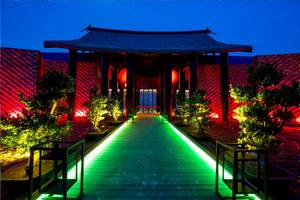 Eingang des Kandima Maldives Hotels bei Nacht mit grünen und roten Lichtern.