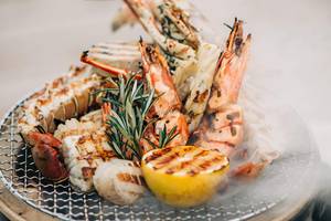 Gegrillter Meeresfrüchte-Platter mit Zitrone und Rosmarin auf einem Grillrost