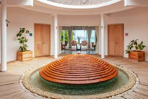 Innenbereich des Finolhu Baa Atoll Maldives Hotels mit einem großen Brunnen und Ausblick auf das Meer.